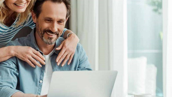 A middle aged couple looking at their laptop to organise their retirement planning journey