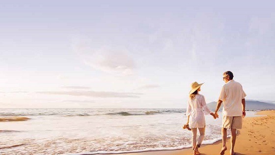 a couple walking hand in hand on a beach after saving a retirement nest egg for retirement