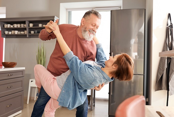a couple dancing in the kitchen celebrating the benefits of financial planning